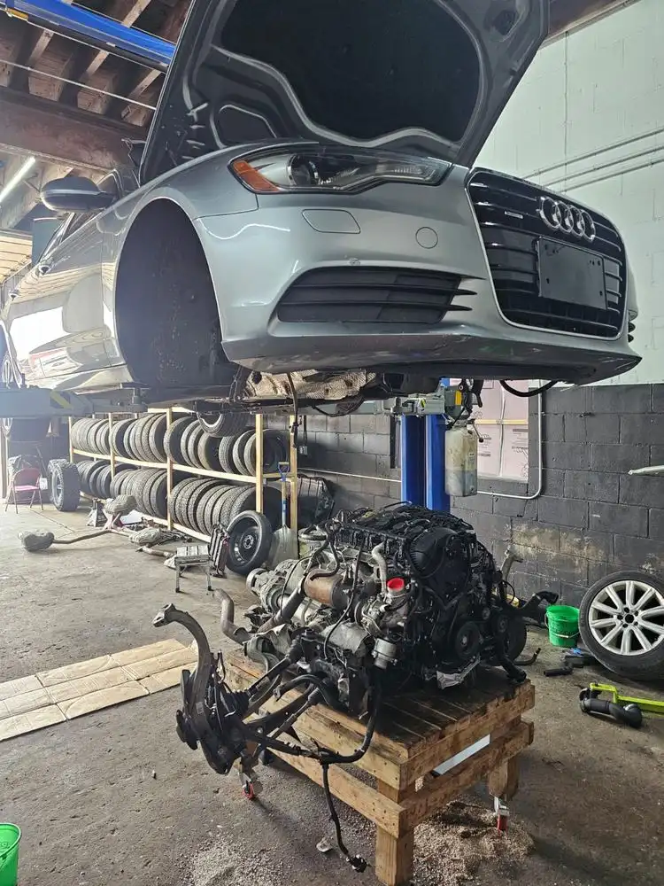 Car on a lift with its engine out on a cart