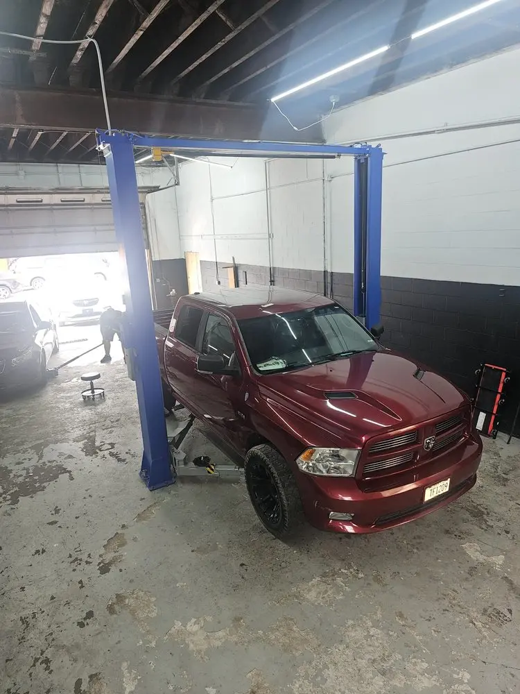 Red pickup truck on a two-post lift in the repair bay